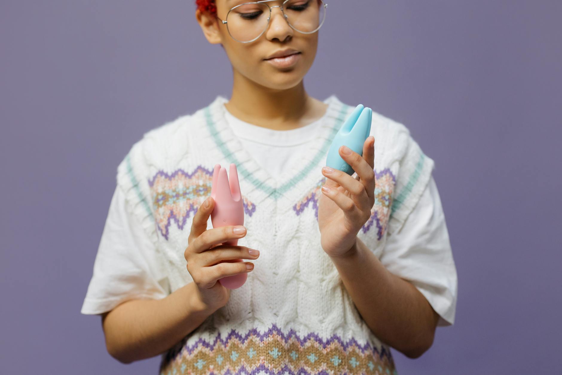 Woman thoughtfully holding colorful clitoral vibrators, representing exploration of pleasure at any age